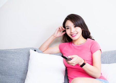 asian woman watch television happily at homeの写真素材
