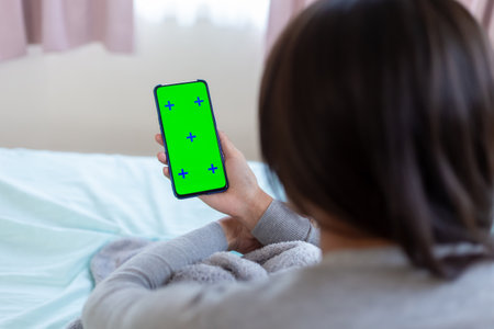 asian female use green screen mobile phone on the bedの写真素材