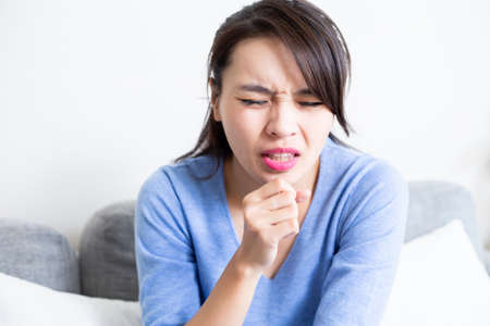 asian woman is sick and coughing in the living room at homeの写真素材