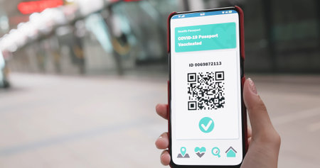 asian woman shows health passport on mobile phone which indicates a vaccination against covid-19...