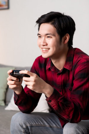 asian man use gamepad and play video games happily in the evening at home