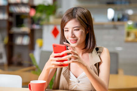 Young woman use mobile phone in coffee shopの写真素材
