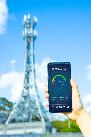 woman holds smartphone with 5g speed test near base station