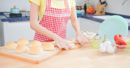 close up of asian pretty woman hands is making freshly baked bread happily in kitchenの写真素材