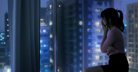 asian woman is tired about over time work and sitting near window at night