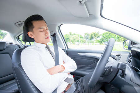 tired asian businessman sleep in car while commuttingの写真素材