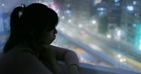 woman looking out of window feel depression at night
