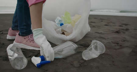 asian woman pick up plastic bottle cleaning the beachの写真素材