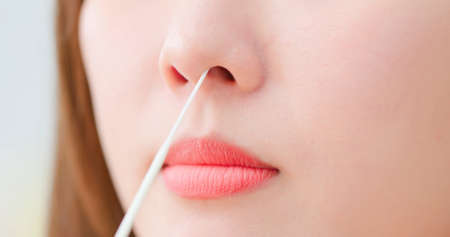 close up of asian woman is putting nasal swab into nose to self test about COVID-19の写真素材