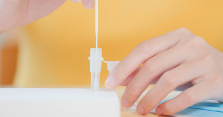 Covid-19 rapid antigen self test process-close up of smiling asian woman placing nasal swab inside...