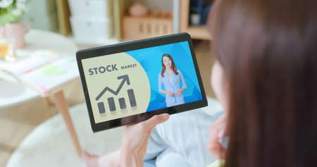 asian woman learns stock market investmention online through digital tablet at homeの写真素材