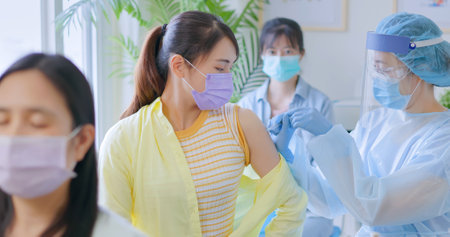 asian woman wearing face mask receiving  vaccine in hospitalの写真素材