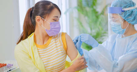 asian woman wearing face mask receiving coronavirus vaccine in hospitalの写真素材
