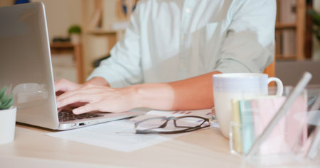 close up of asian man typing on laptop at home