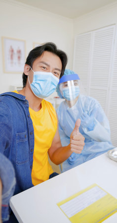 asian man wears face mask taking selfie with mobile phone when getting vaccinated  and thumb up with...