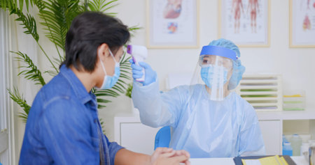 asian female doctor is measuring man temperature for vaccination at hospital