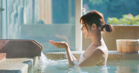 slow motion of asian woman scoop up hot spring by hands to feel the water-Human hand cupped to catch the fresh waterの写真素材