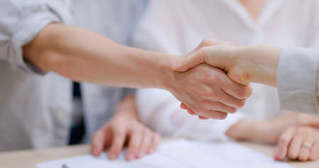 close up of asian couple are signing a contract to buy real estate or finance investment insurance contract and they shake hands with sales at homeの写真素材