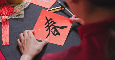 close up of asian woman finish writing Chinese festival couplet to celebrate new year with word meaning springの写真素材