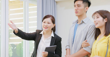 asian young couple with real estate agent visiting house for sale or rent - close up of realtor...