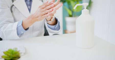 close up of asian female doctor uses alcohol for hand disinfection in hospitalの写真素材