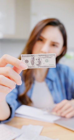 inflation concept - worried asian woman find money is getting smaller at kitchen