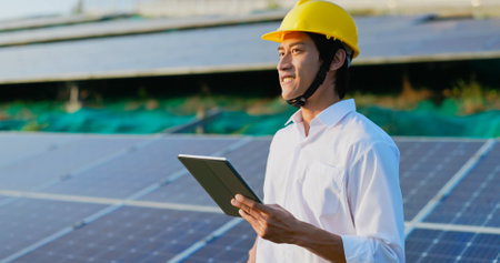 asian male business man holding digital tablet on the field to check solar power stationの写真素材