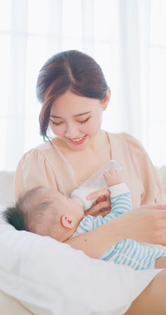 authentic shot of asian mother feeds her baby from bottle and she feels happiness