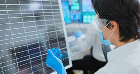 asian engineer team are working with computer and a man examining solar panel through transparent...