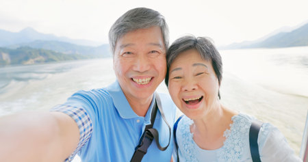 Authentic shot of asian elderly couple have video chat by mobile phone happily on boat in close up