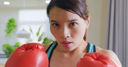 asian sweating sport woman doing boxing training at homeの写真素材
