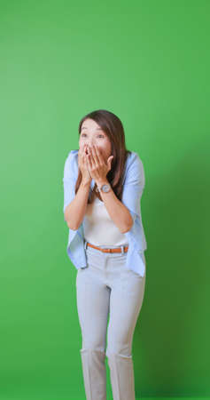 asian female woman standing in front of green background is excited about getting some goods surprise news with fist gestureの写真素材