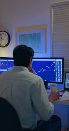 rear view of asian man has stock market or cryptocurrency investment from home by computer and he is...