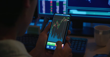 asian man has stock market or cryptocurrency investment from home by computer with mobile phone and...