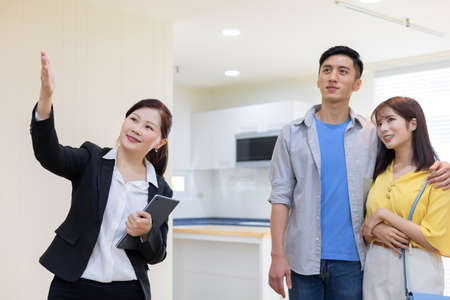 asian young couple with real estate agent visiting house for sale or rent - realtor introduces buildingの写真素材