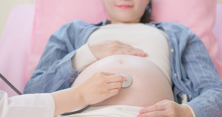 close up of asian female doctor exams a pregnant woman lying in hospital ward by stethoscopeの写真素材