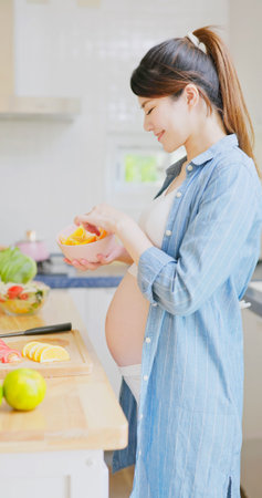 Vitamin C supplementation for Pregnancy - asian pregnant woman is eating oranges and there are...