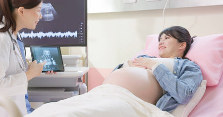 asian pregnant woman lying in hospital ward has uterus utltrasonographic diagnosis - female doctor...