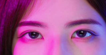 close up of female cyber sport gamer eyes with neon lightの写真素材