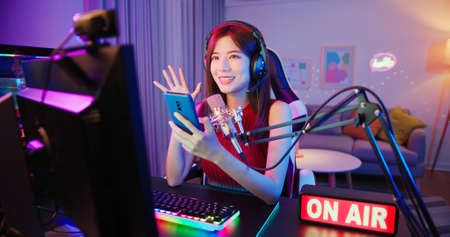 asian female cybersport gamer have live stream with on air light sign and playing mobile game by the smartphone at homeの写真素材