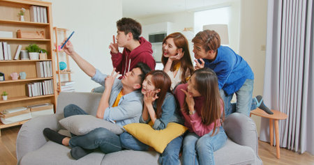 side view of happy asian friends taking selfies together in room on sofa with smartphone