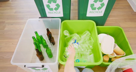 point of view - kid sorting garbage at home recycling rusing glass plastic and paper for sustainable...
