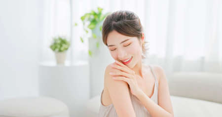 beauty skin care asian woman with brunette ponytail touches her shoulder eye closedの写真素材