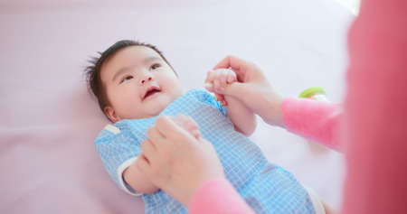 authentic shot of asian mother plays with her baby on the bedの写真素材