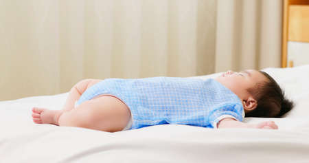 close up of asian baby is sleeping alone on the bedの写真素材