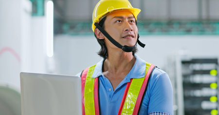 close up of young asian engineer inspecting power supply system by laptop on his hand and look...