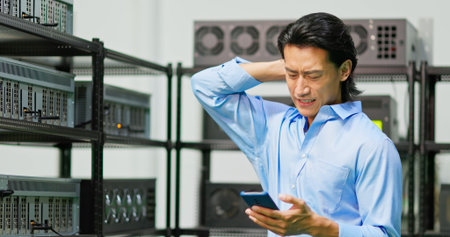 young asian businessman checking his crypto currency benefit by cellphone and worrying about his earnings decreaseの写真素材