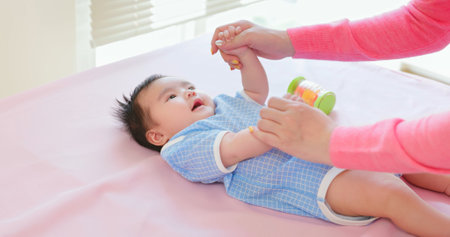 authentic shot of asian mother plays with her baby on the bedの写真素材