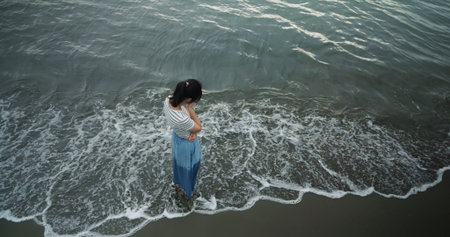 depression and melancholy concept - top view of asian woman wearing blue skirt is standing at beach...