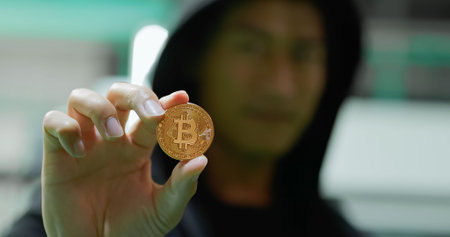 young asian hacker showing bitcoin in his hand stole from mining farm investors